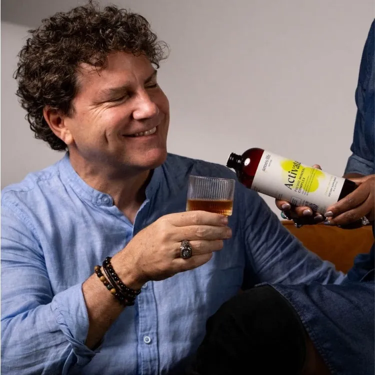 A man smiling as he pours Ameo Life Activate into a glass